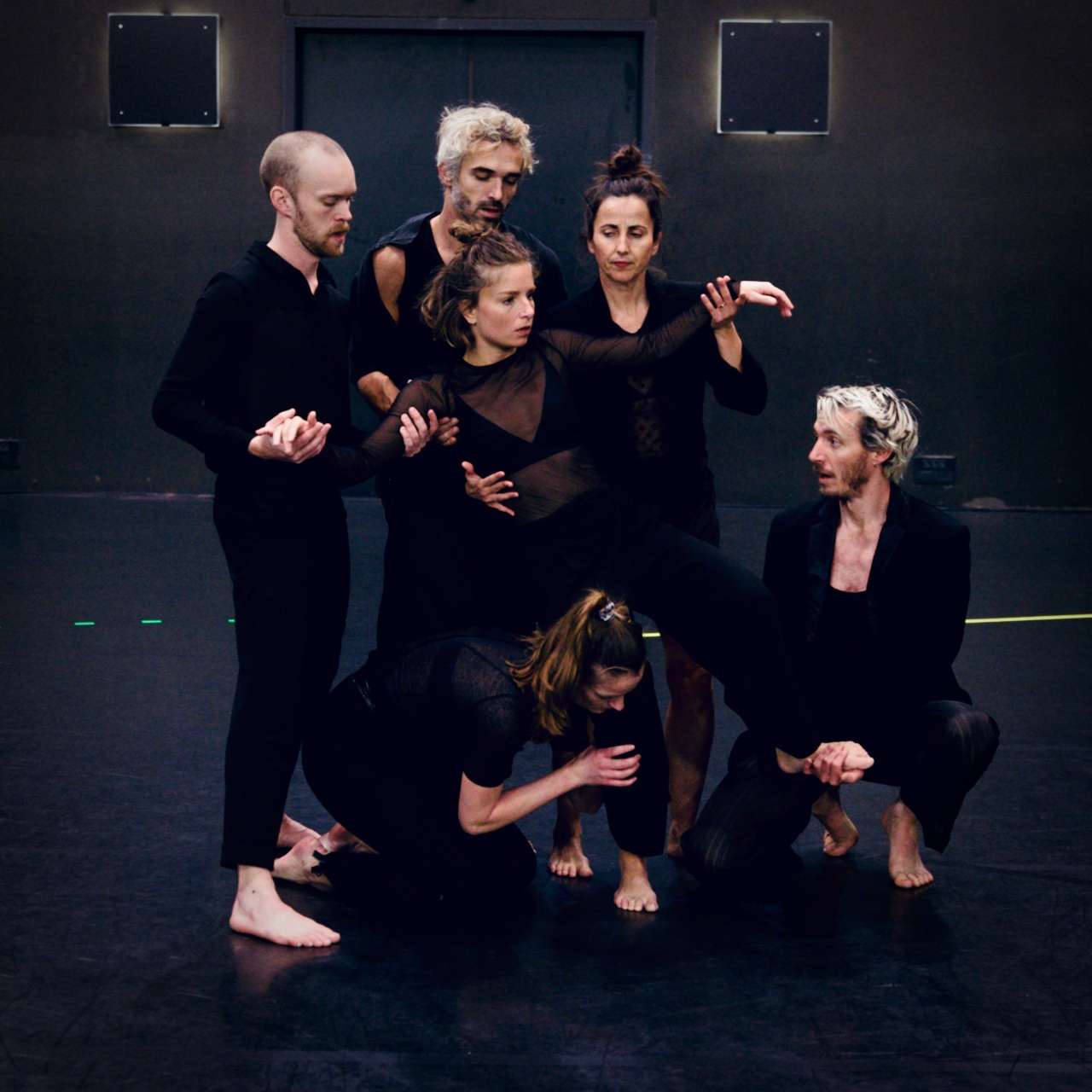 Photo d'une des représentations de "The Way Things Go". L'ont retrouve les six danseurs(euses) au plateau, une des danseuses au centre de l'image est en équilibre sur une jambe tandis que les cinq autres la soutienne.