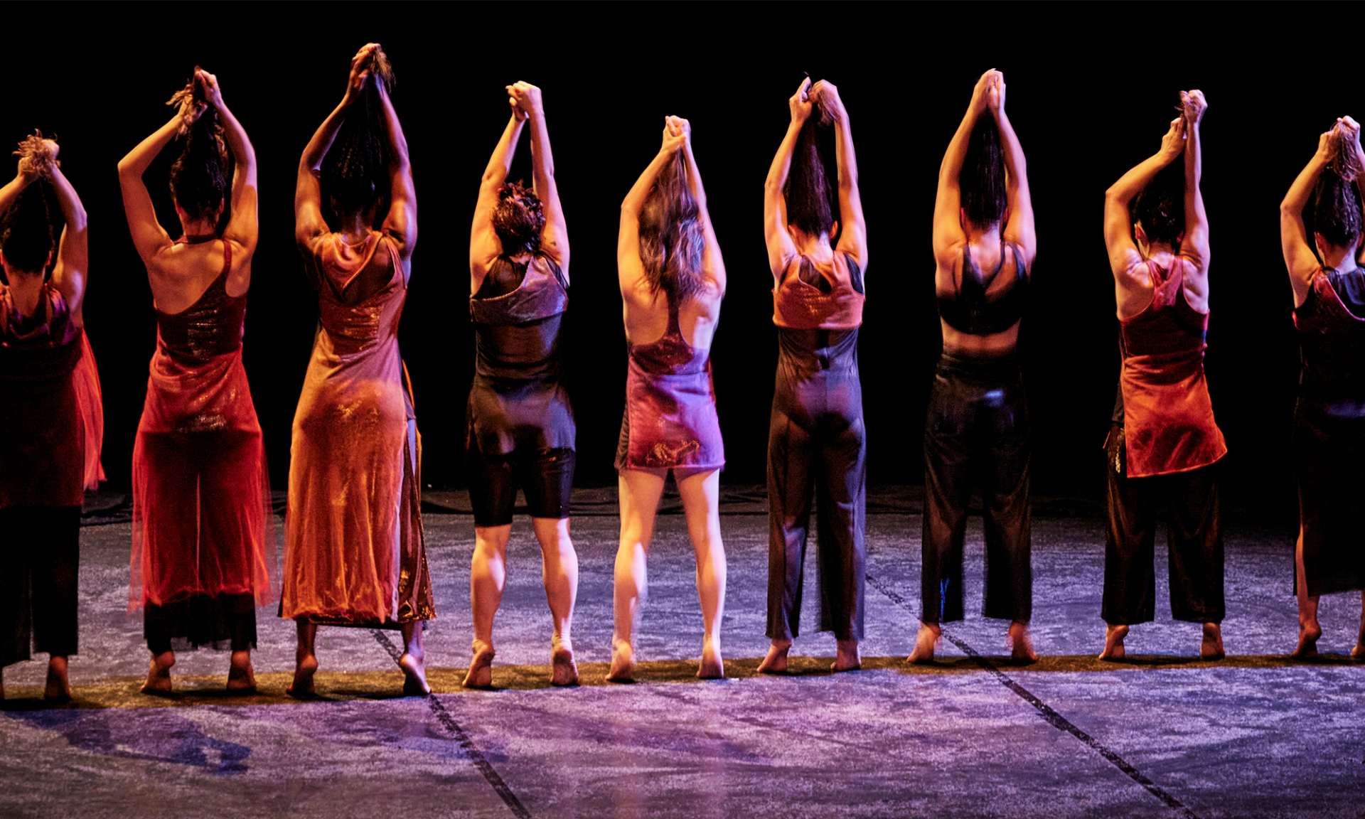 Photo du spectacle "Fêu" où les danseuses se tiennent de dos, tendant leurs cheveux au dessus de leur tête