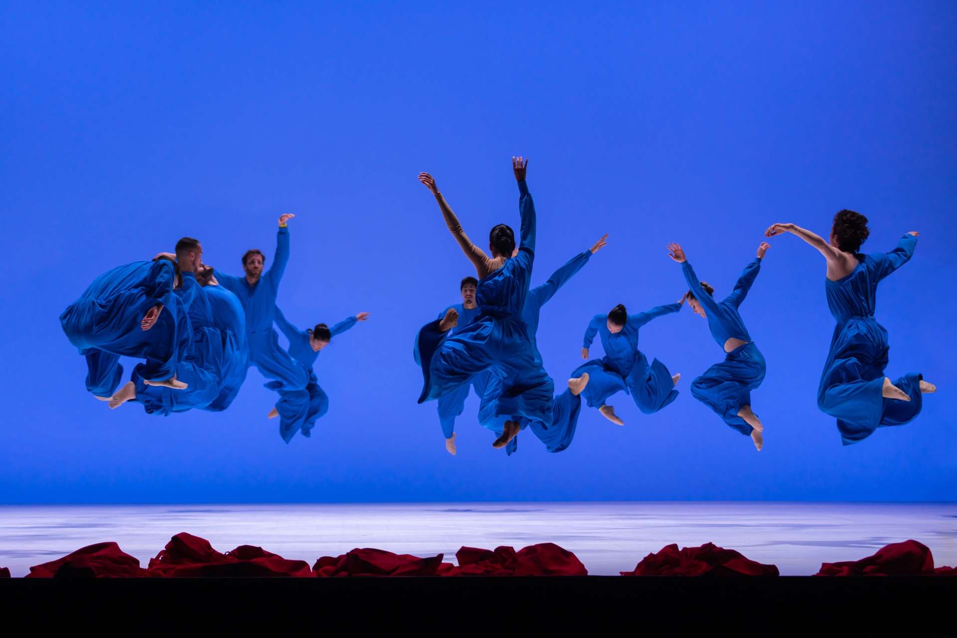 Les danseurs et danseuse de "Vïa" sautent en l'air dans leur costume bleu.